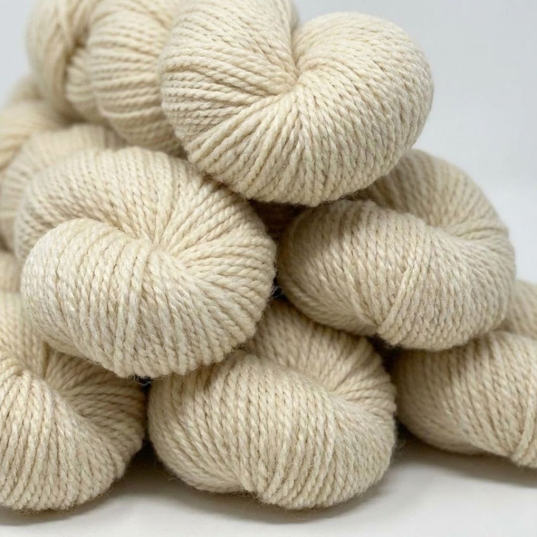 several skeins of natural, cream-colored merino wool showing their soft, crimped texture