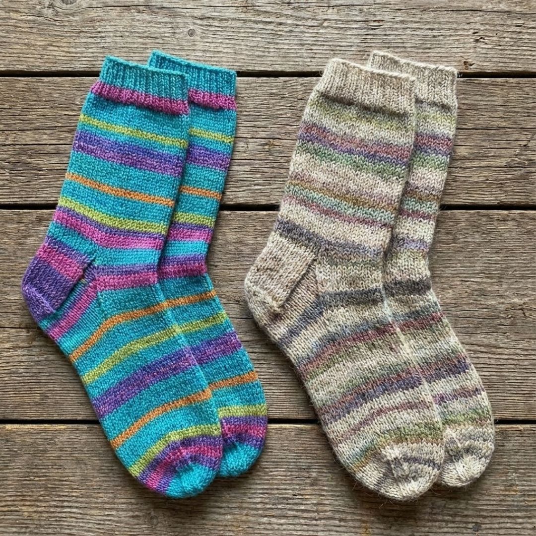 Two pairs of hand-knit socks side-by-side, one made from smooth superwash wool and the other from more rustic non-superwash wool